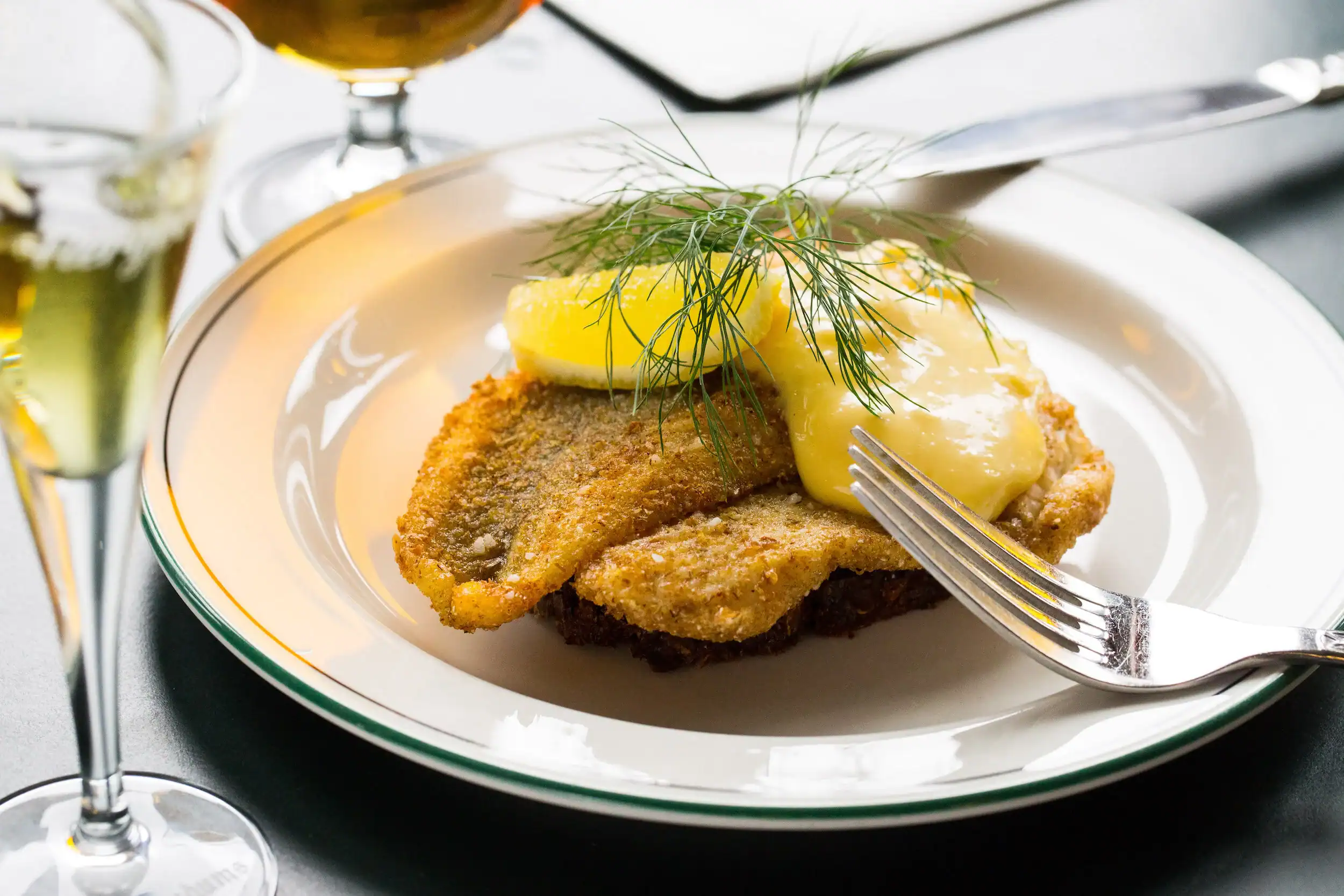 fiskefilet med remoulade serveret på tallerken sammen med en snaps og en pilsner