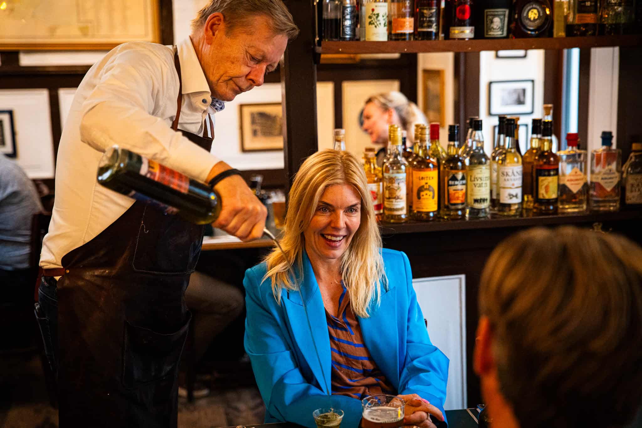 kvinder smiler mens tjener skænker snaps i hendes glas
