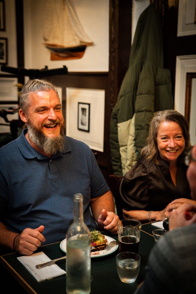 smilende gæster sidder ved et bord i krostuen